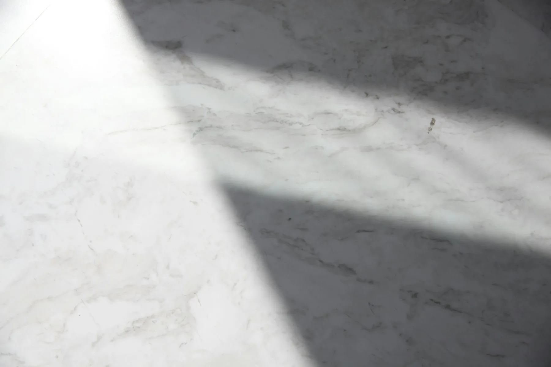 Close-up of white marble-pattern porcelain surface in raking light