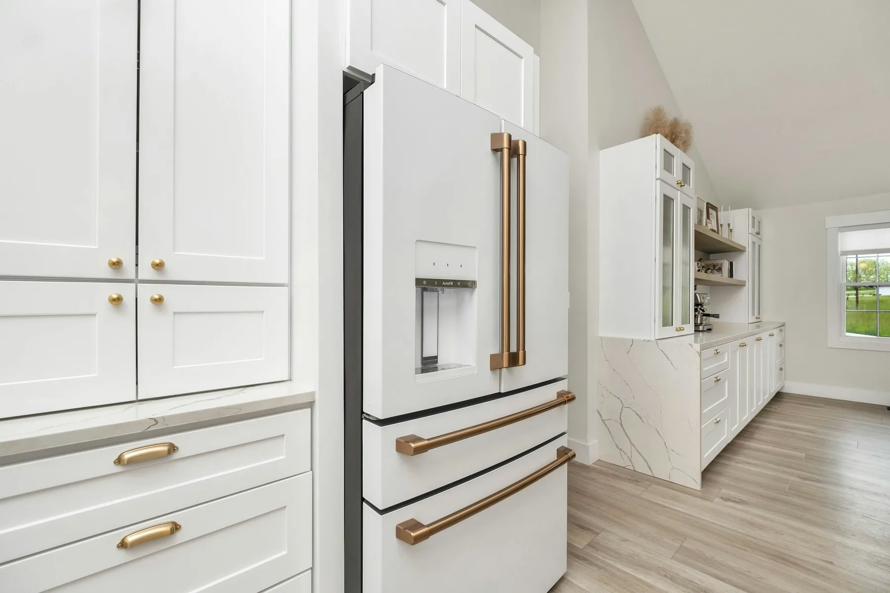 Panel-ready refrigerator with brass hardware and white shaker cabinet fronts