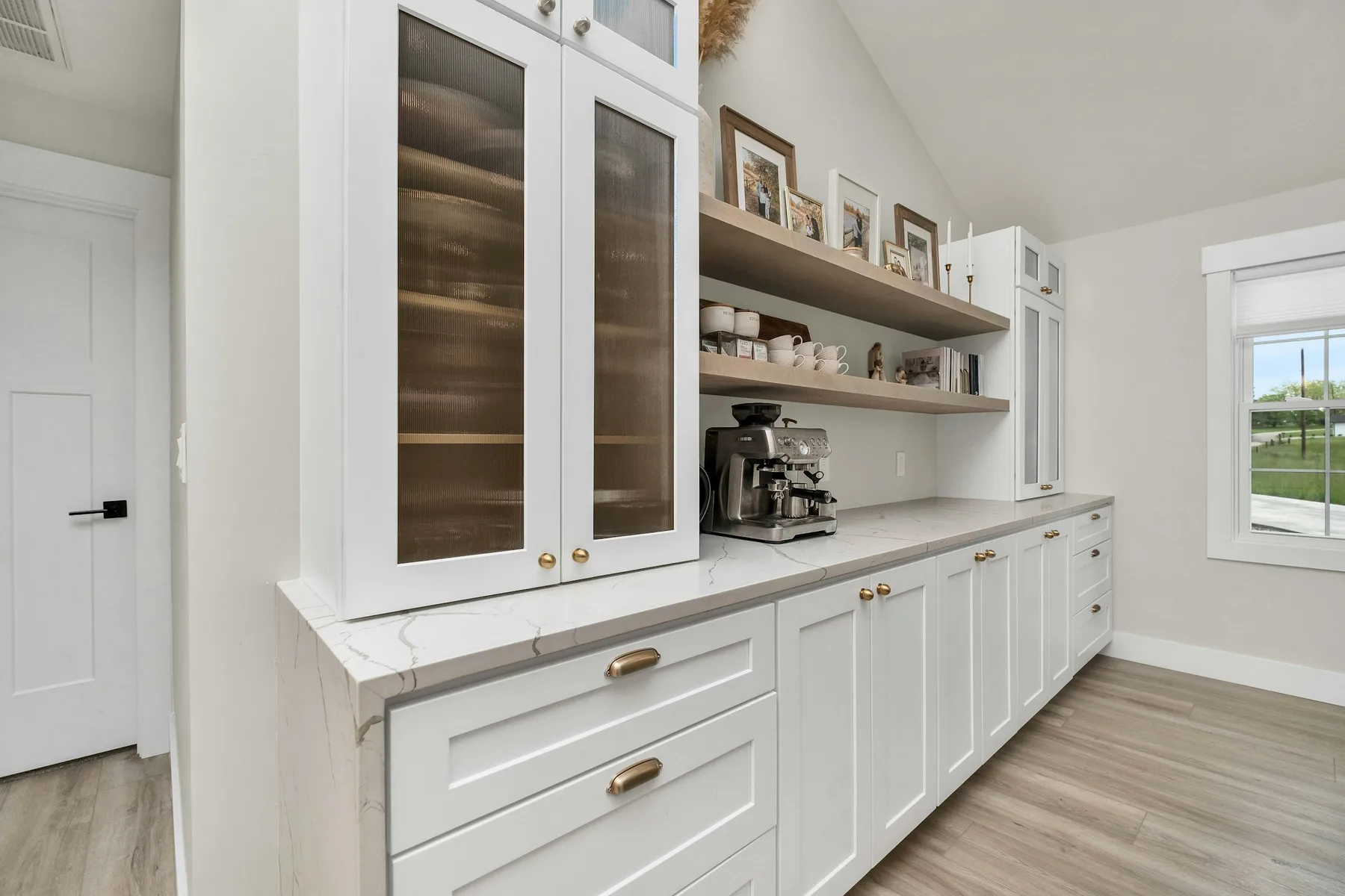 Coffee bar with glass upper cabinet, open shelf and white cabinetry
