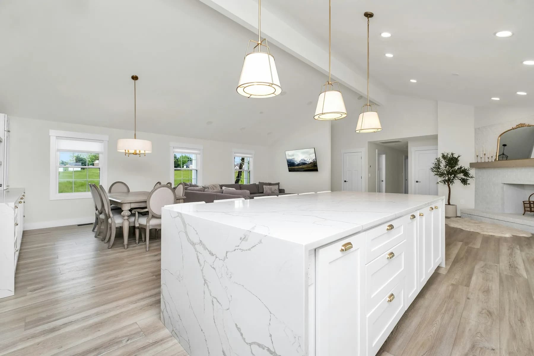 Marble waterfall island with dining table and pendant lighting beyond