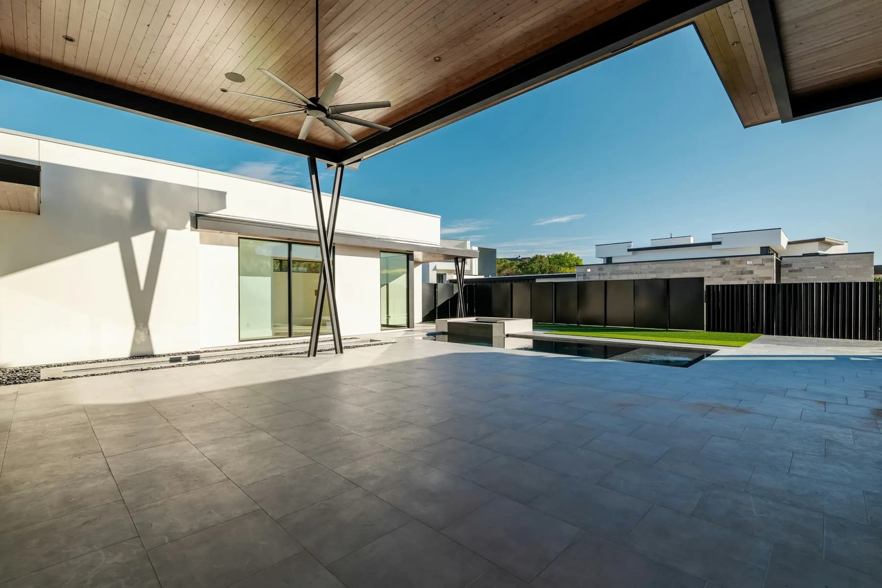 Large covered patio with exposed structure, ceiling fan and large-format paving