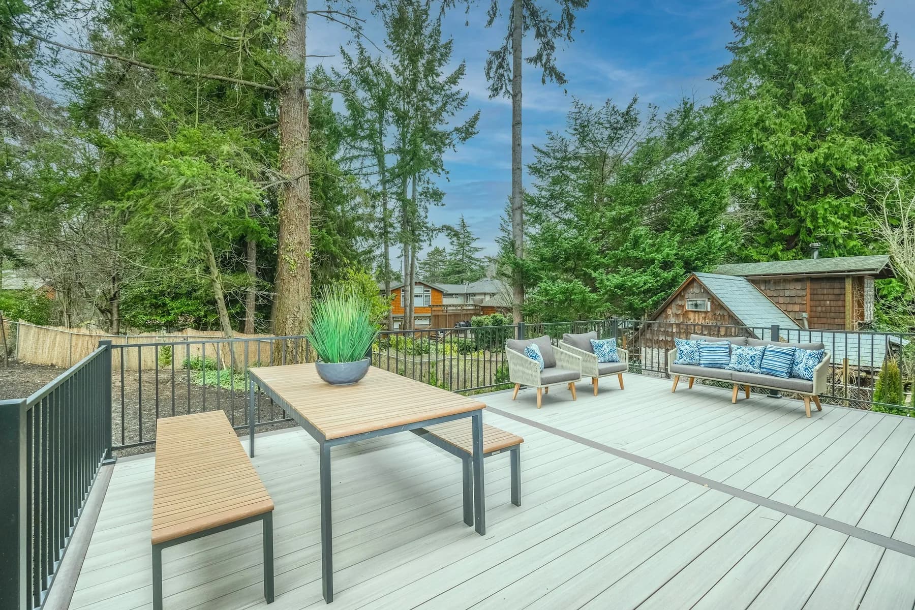 Composite deck with outdoor dining table, bench seating and black railing