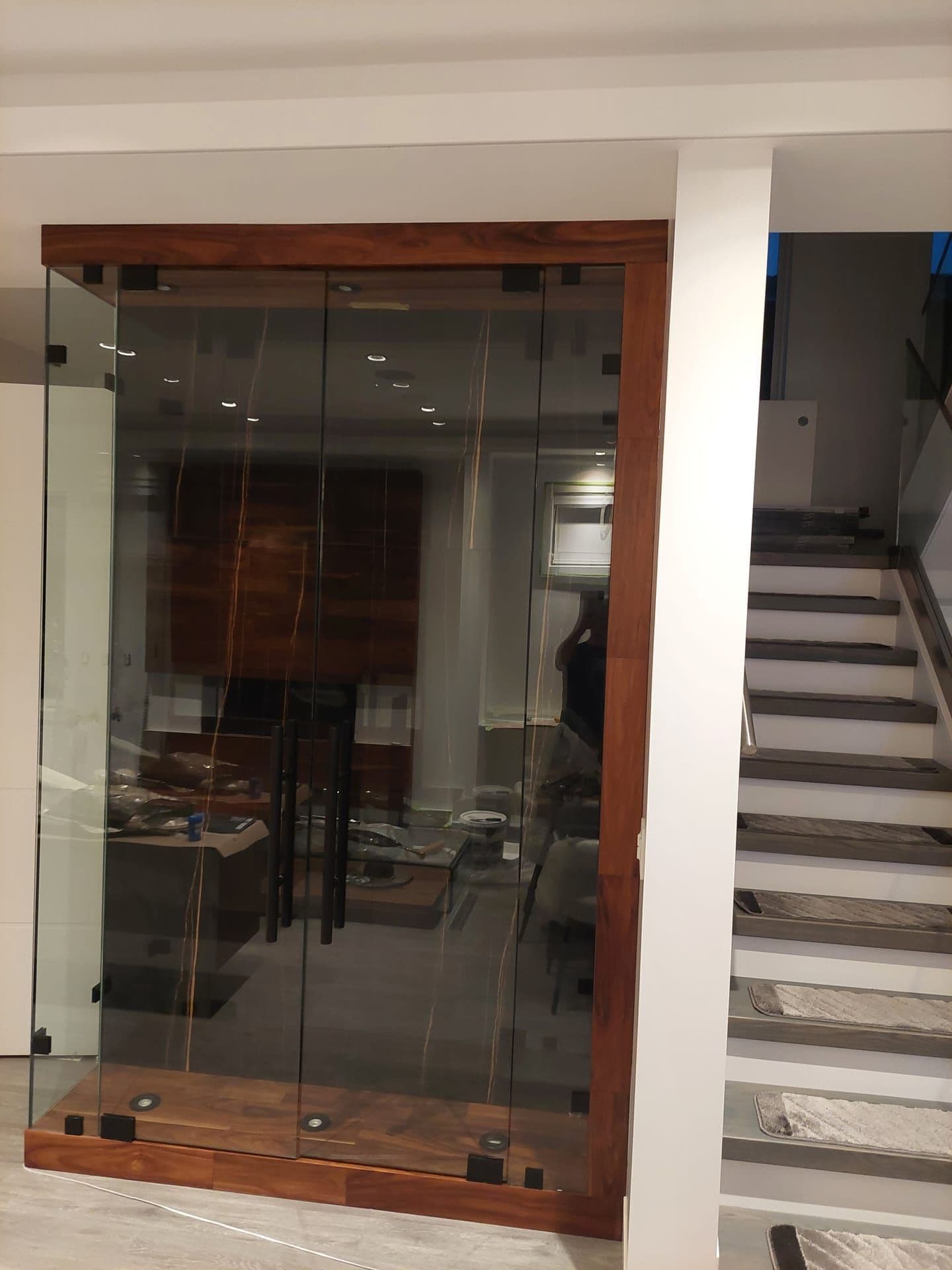 Custom wine cellar with glass enclosure and walnut frame — luxury home renovation
