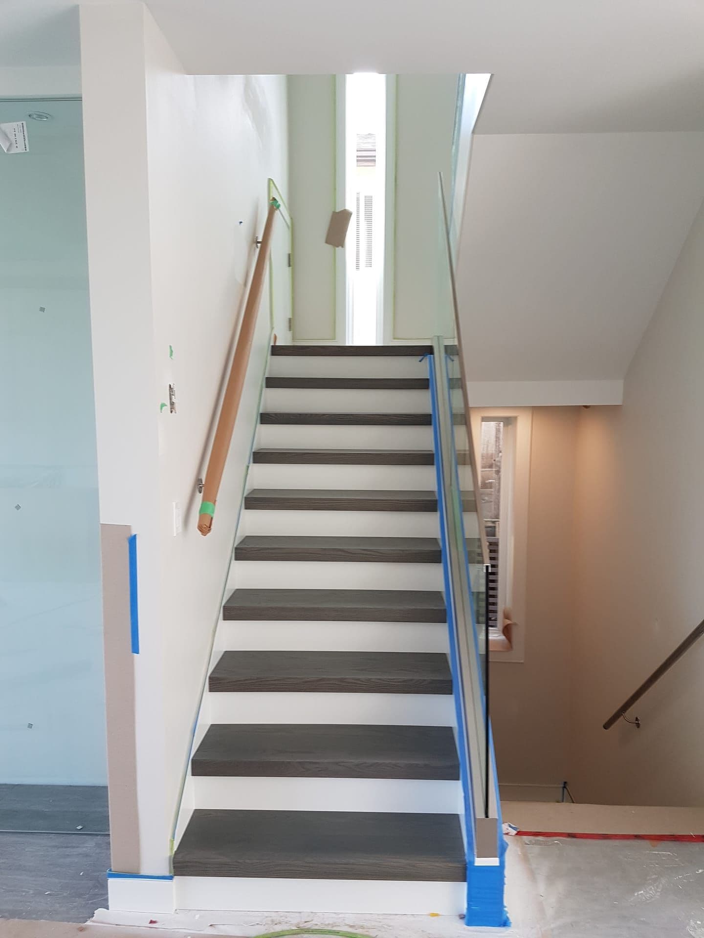 Modern staircase renovation with dark treads and glass railing in Lower Mainland home